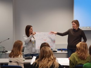 Two teachers holding up their map showing their work to the whole group